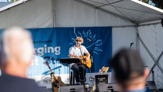 A solo guitarist on stage at the 2025 Festival of Sails Emerging Artist Series performing to a crowd