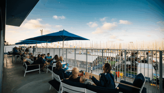 Sailors gather on the balcony of the Victorian Sailing Centre, soaking up the atmosphere of Festival of Sails from the Sailors Lounge.