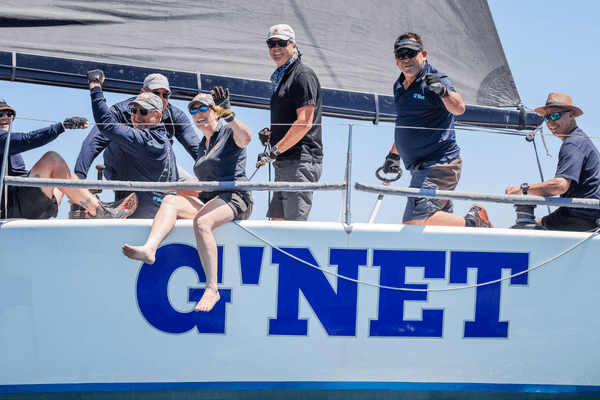 The G'NET crew wave at the camera during Festival of Sails 2026. They will join the fleet again as the first entrants for 2027.