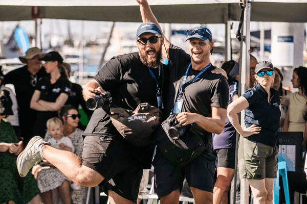 Two members of the Sunset Media team pose with their equipment during presentations of the 2026 Festival of Sails. 